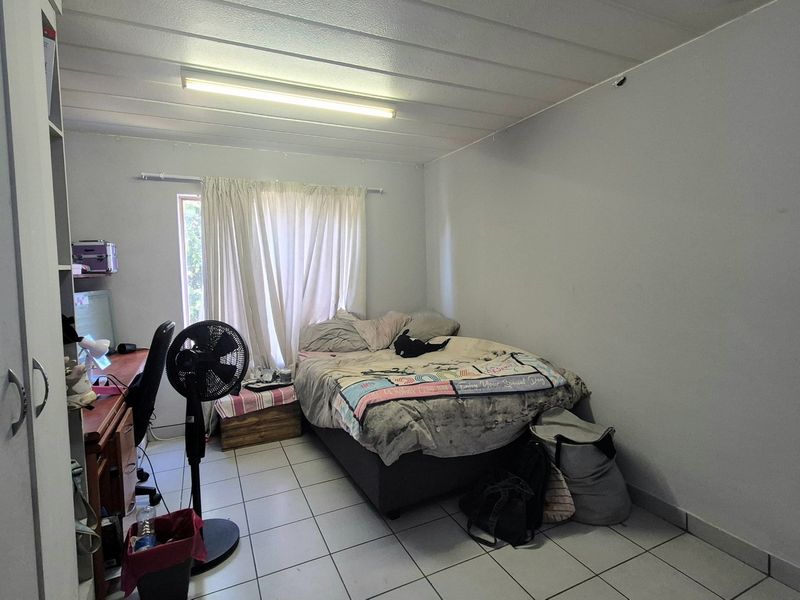 A functional bedroom featuring tiled flooring, a built-in wardrobe, and a standard ceiling light fixture.