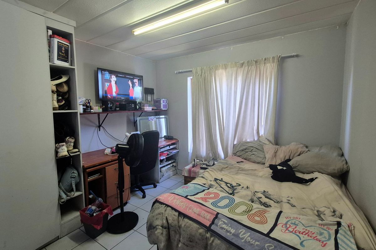 A functional bedroom featuring tiled flooring, a built-in wardrobe, and a standard ceiling light fixture.