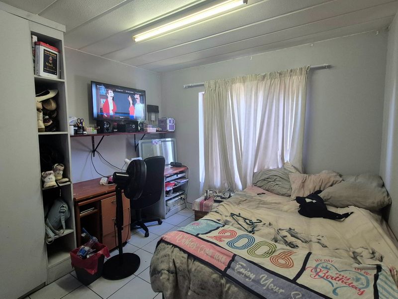 A functional bedroom featuring tiled flooring, a built-in wardrobe, and a standard ceiling light fixture.