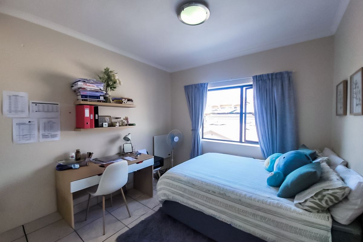 A functional bedroom featuring tiled flooring, a central ceiling light, and a window with curtain tracks, providing a comfortable living space.