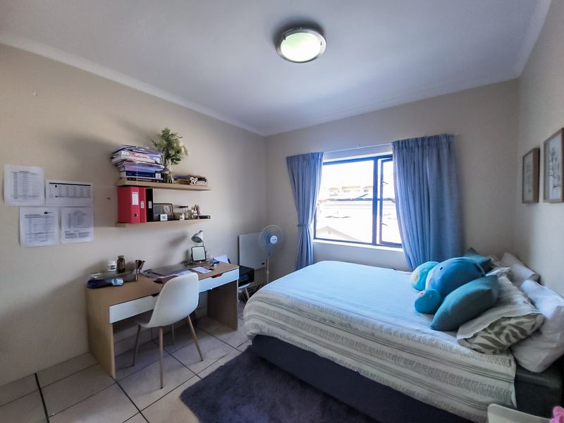 A functional bedroom featuring tiled flooring, a central ceiling light, and a window with curtain tracks, providing a comfortable living space.