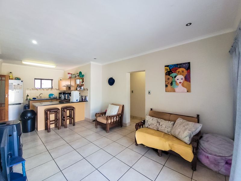 Open-plan living area featuring a functional kitchen with granite countertops, tiled flooring throughout, and recessed lighting, creating a versatile space for living and dining.