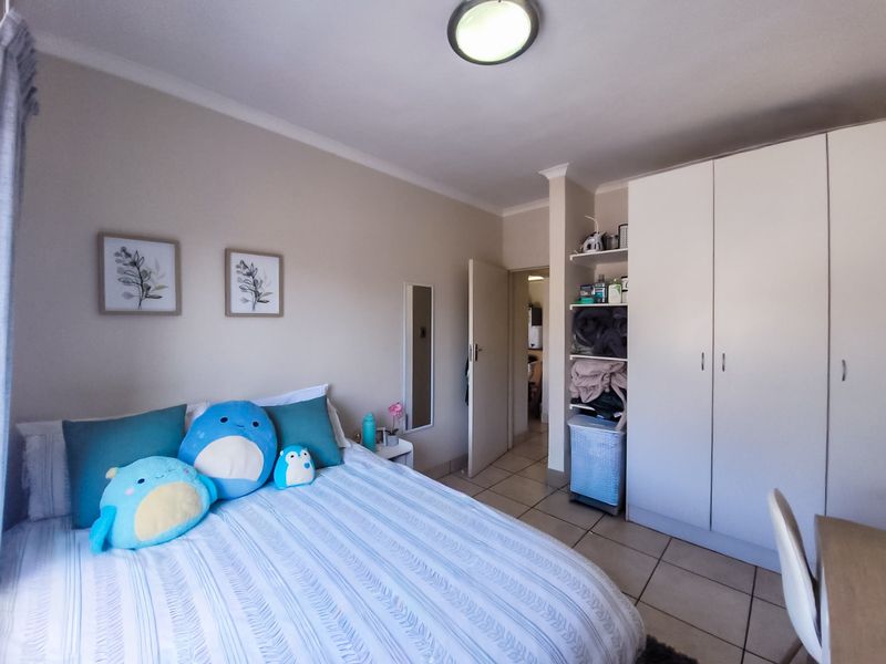 A bedroom featuring tiled flooring, a built-in wardrobe with open shelving, and a ceiling light fixture.