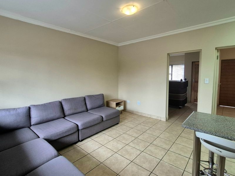 Open plan living area featuring tiled flooring and a breakfast counter, providing a functional space with access to adjacent rooms.