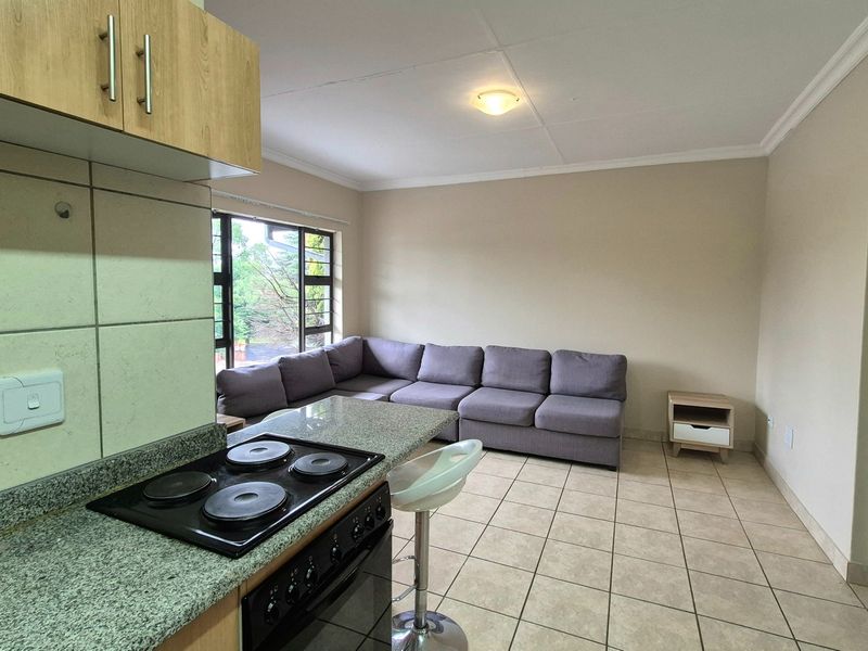 Open-plan living area featuring a functional kitchen with granite countertops, built-in stove and oven, and neutral tiled flooring throughout.