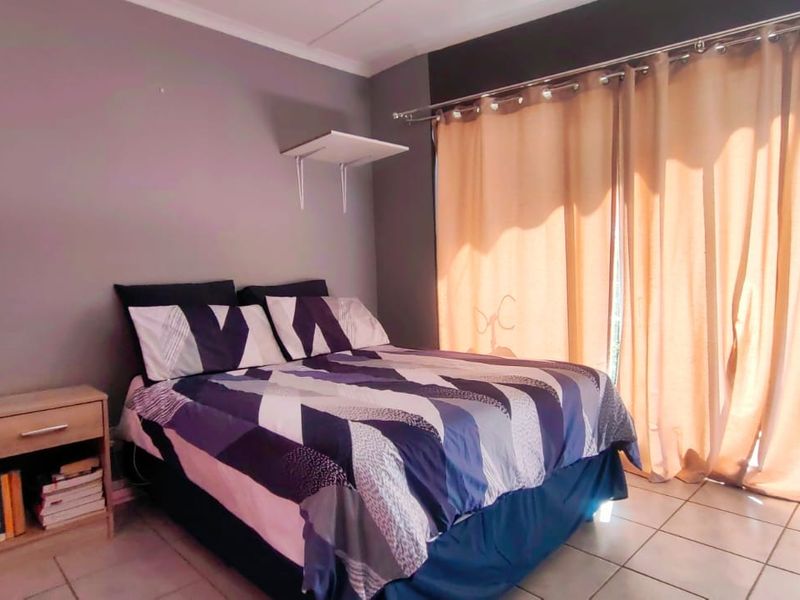 A bedroom featuring tiled flooring and a sliding glass door with curtain rails, providing access to an outdoor area.