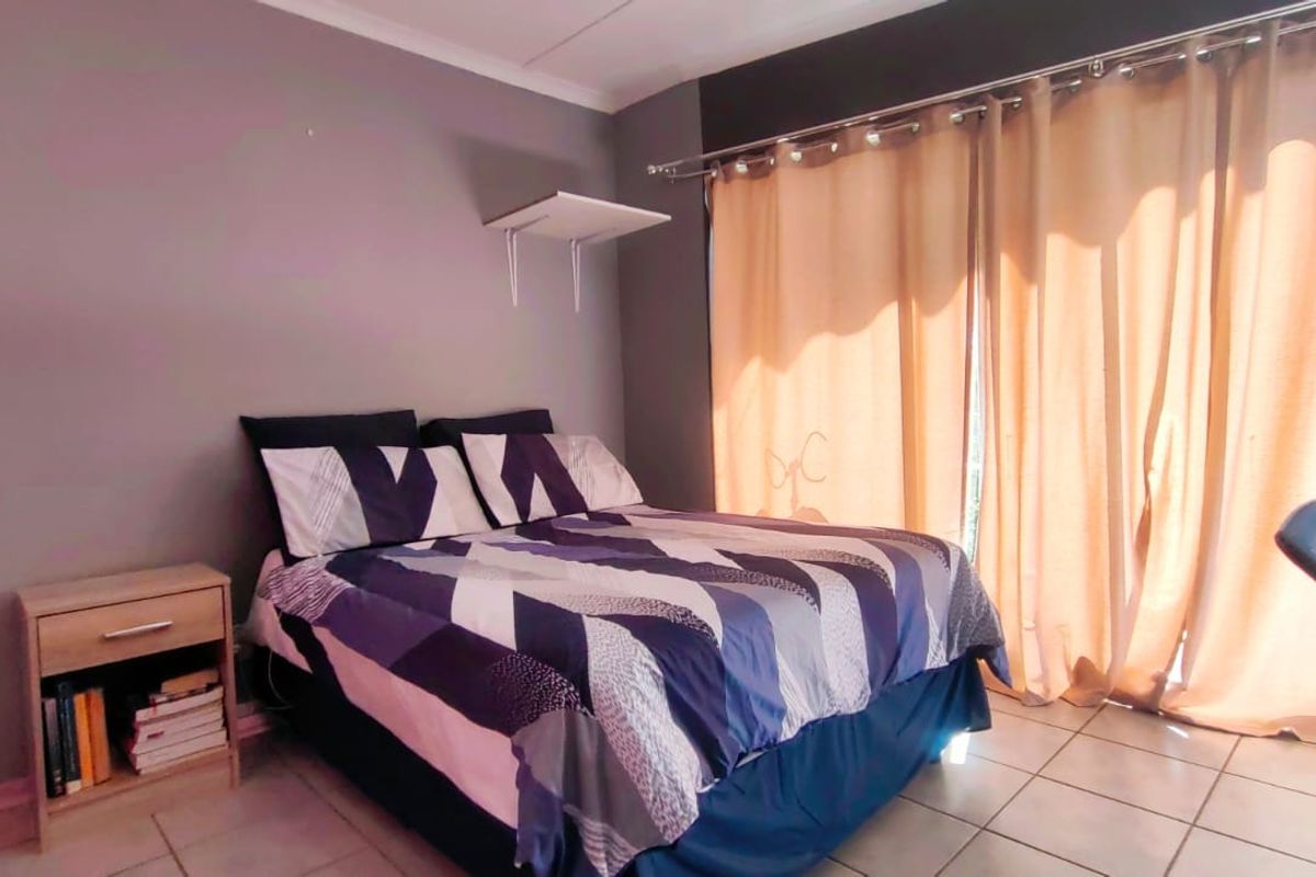 A bedroom featuring tiled flooring and a sliding glass door with curtain rails, providing access to an outdoor area.
