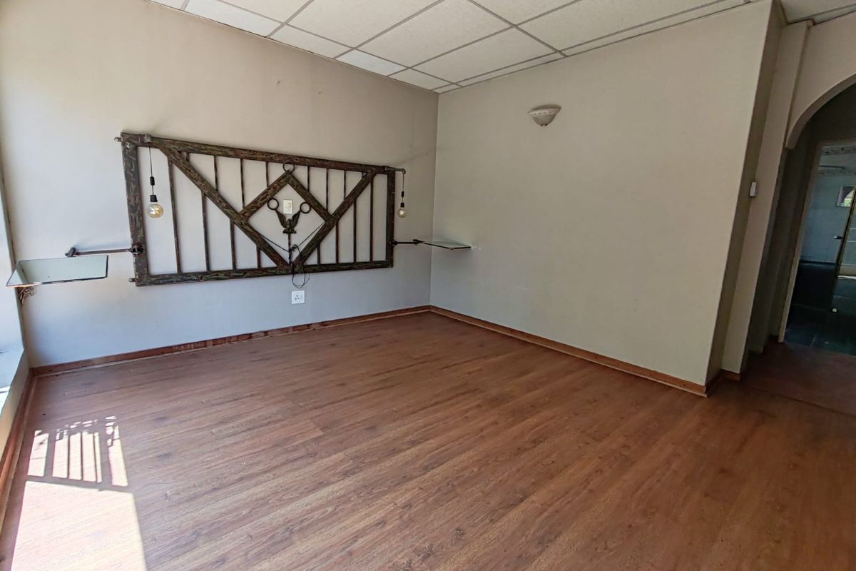 An empty bedroom featuring laminate flooring, a drop ceiling, and wall-mounted lighting fixtures, offering a blank canvas for personalization.