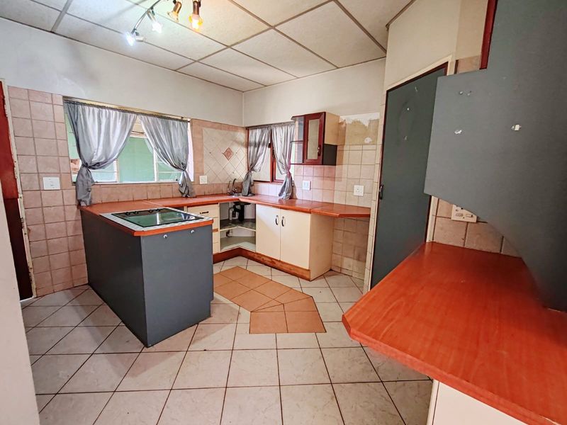 A dated kitchen featuring tiled flooring, laminate countertops, and a built-in hob, offering significant potential for modernization and renovation.