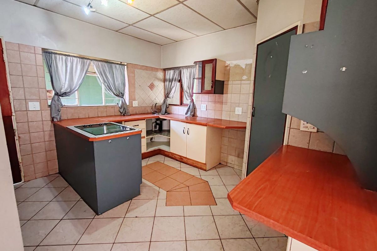 A dated kitchen featuring tiled flooring, laminate countertops, and a built-in hob, offering significant potential for modernization and renovation.