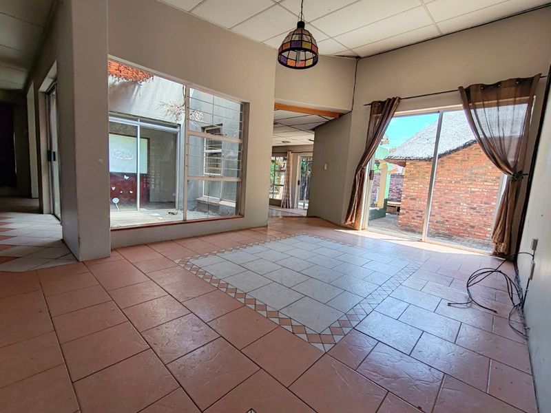 Spacious living area featuring large sliding glass doors, expansive windows, and tiled flooring, offering a bright, open layout with direct access to the exterior.