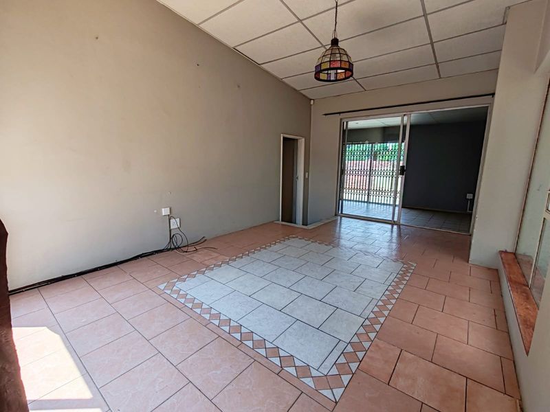 An empty living area featuring tiled flooring with a decorative inlay, a drop ceiling, and a sliding glass door leading to an outdoor space.
