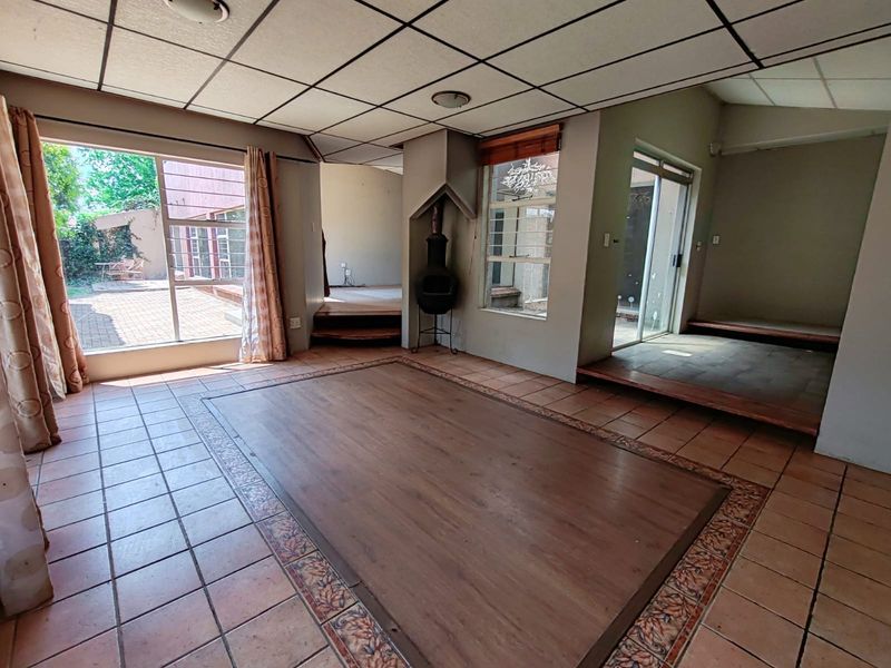 Spacious living area featuring tiled floors with a wood laminate inlay, a freestanding fireplace, and large sliding glass doors leading to the outdoor patio.