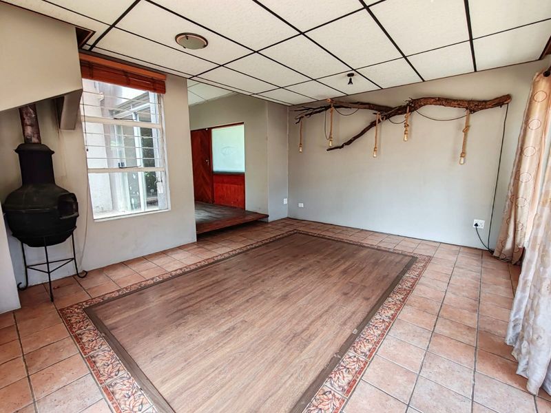 Spacious living area featuring a freestanding fireplace, tiled flooring with a central laminate inlay, and a drop ceiling.