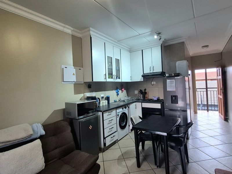 Open-plan kitchen and living area featuring tiled flooring, built-in cabinetry, and direct access to an outdoor balcony.
