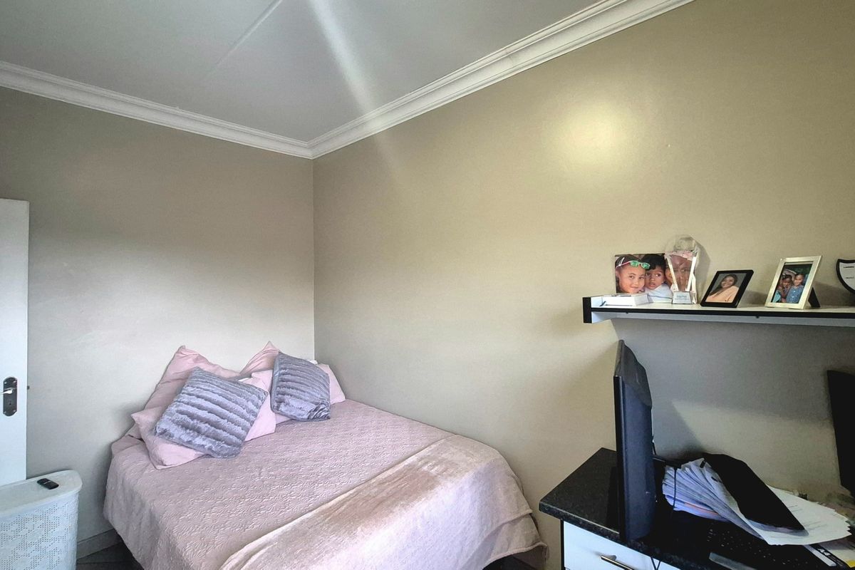 A compact bedroom featuring neutral wall tones, crown molding, and built-in shelving, providing a functional space for rest or study.