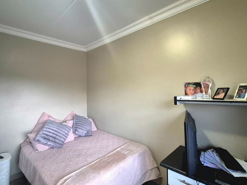 A compact bedroom featuring neutral wall tones, crown molding, and built-in shelving, providing a functional space for rest or study.