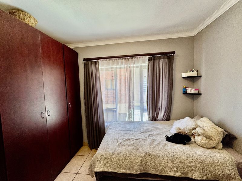 A bedroom featuring tiled flooring, a large built-in wardrobe, and floating wall shelves, providing functional storage space.