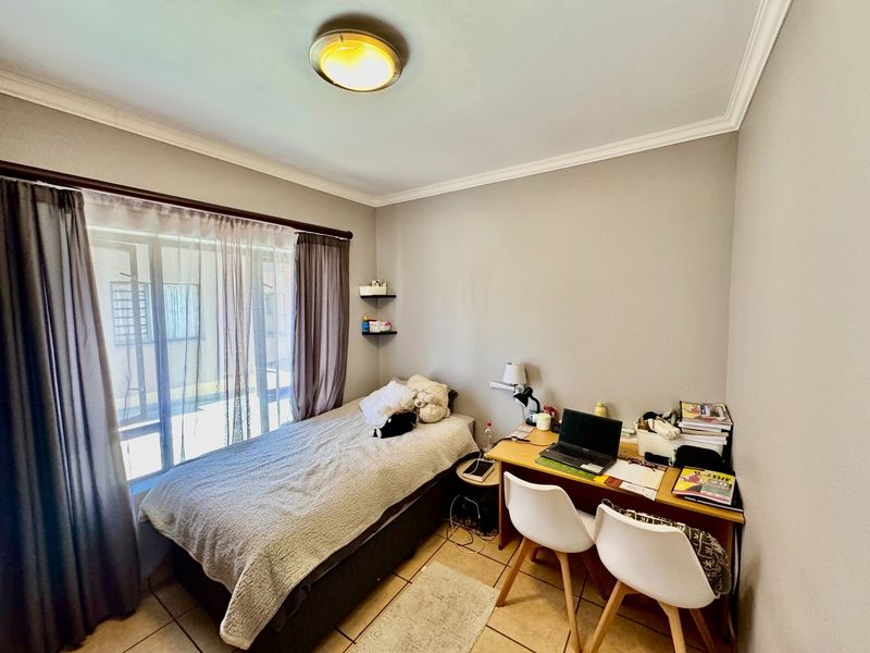 A functional bedroom featuring tiled flooring, a sliding glass door providing natural light, and classic ceiling cornice detailing.