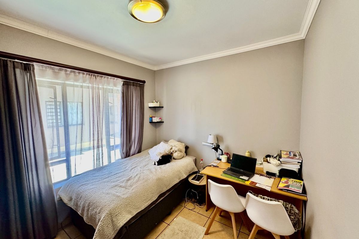 A functional bedroom featuring tiled flooring, a sliding glass door providing natural light, and classic ceiling cornice detailing.