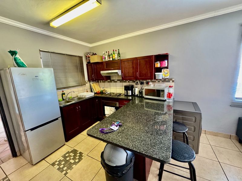 A functional kitchen featuring dark wood cabinetry, granite countertops, a breakfast bar, and tiled flooring, providing a practical workspace for daily cooking.