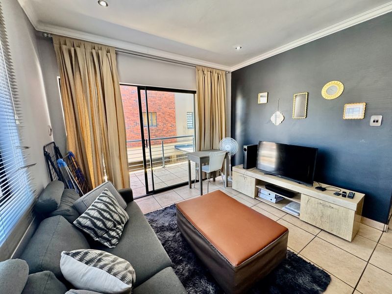 A living room featuring tiled flooring, recessed lighting, and a sliding glass door providing direct access to an outdoor balcony.