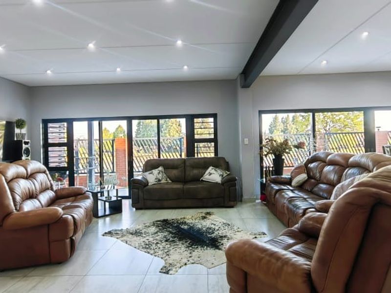 Spacious living area featuring tiled flooring, recessed downlighting, an exposed structural steel beam, and large sliding glass doors providing ample natural light.
