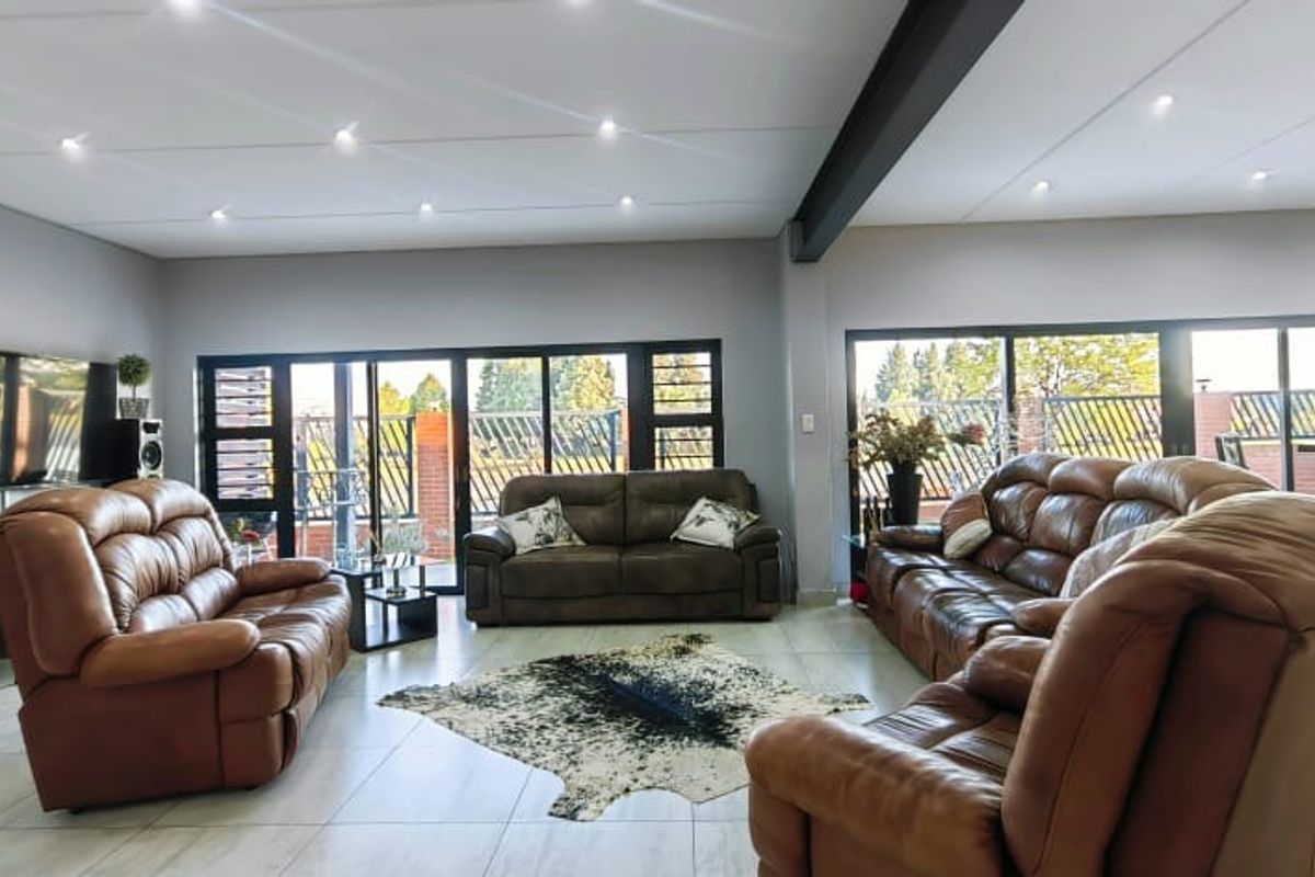 Spacious living area featuring tiled flooring, recessed downlighting, an exposed structural steel beam, and large sliding glass doors providing ample natural light.