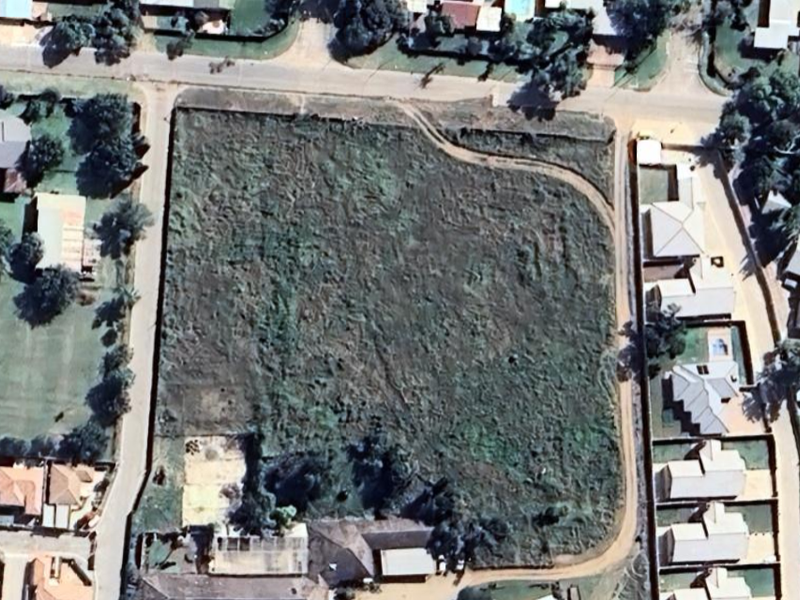 An aerial view of a large, undeveloped residential plot situated within an established suburban neighborhood.