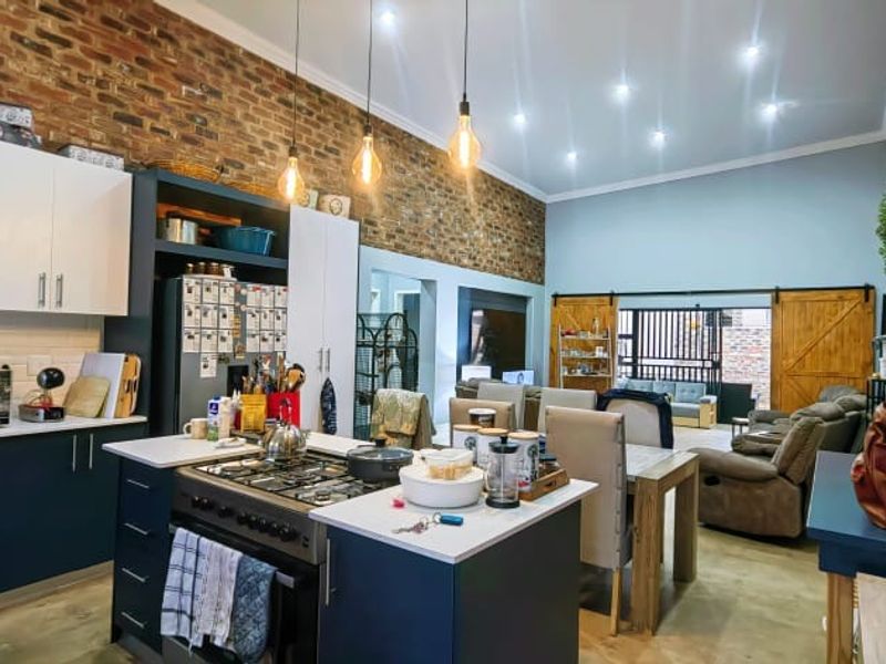 Spacious open-plan kitchen and living area featuring exposed brick walls, modern cabinetry, a gas hob, and sliding barn doors leading to the exterior.