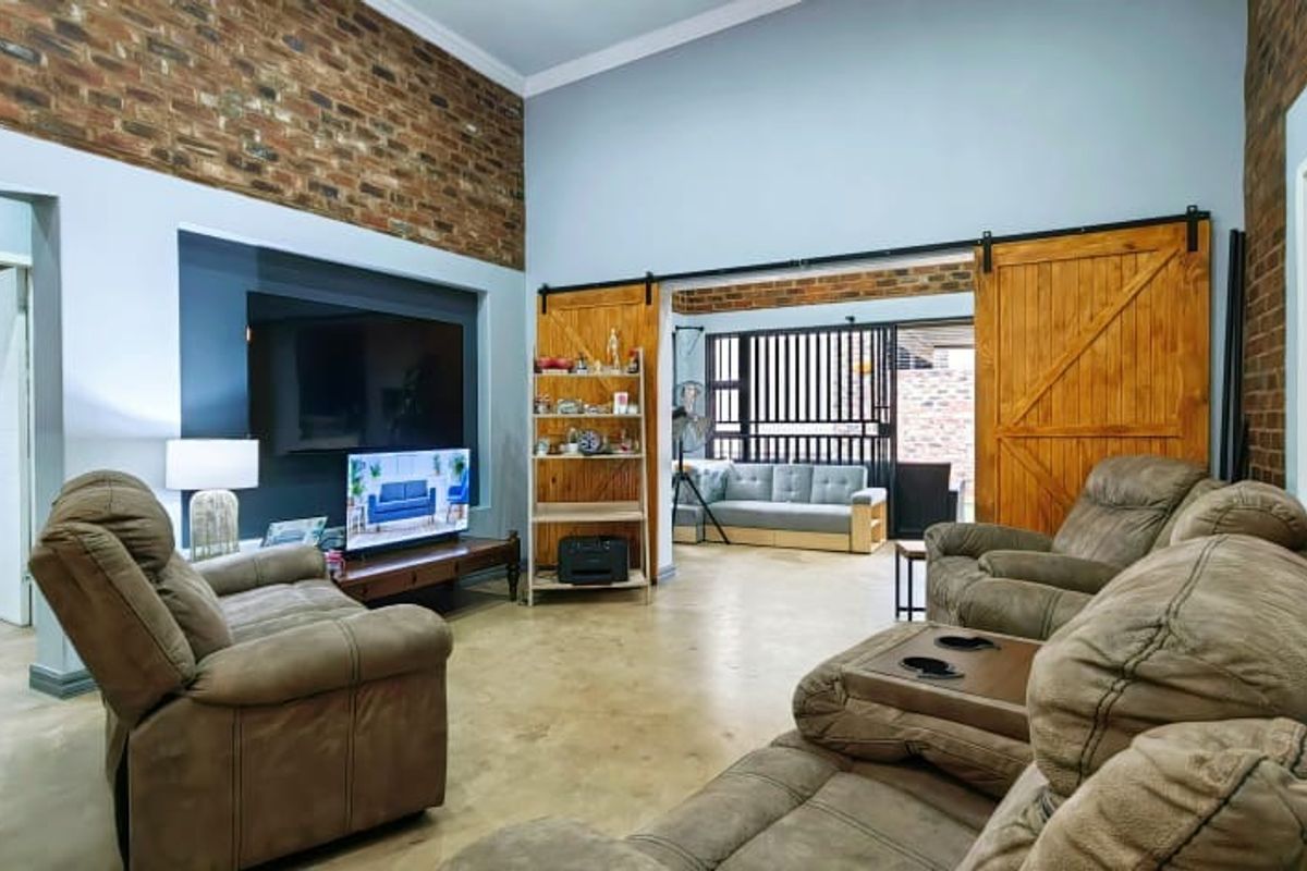 Spacious living room featuring exposed brick walls, polished concrete floors, and rustic sliding barn doors leading to an adjacent area.