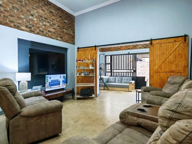 Spacious living room featuring exposed brick walls, polished concrete floors, and rustic sliding barn doors leading to an adjacent area.