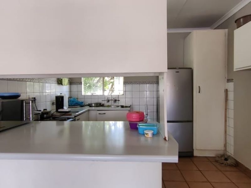 A functional kitchen featuring a breakfast bar, tiled backsplash, ample cabinetry, and tiled flooring, offering a practical layout for daily use.