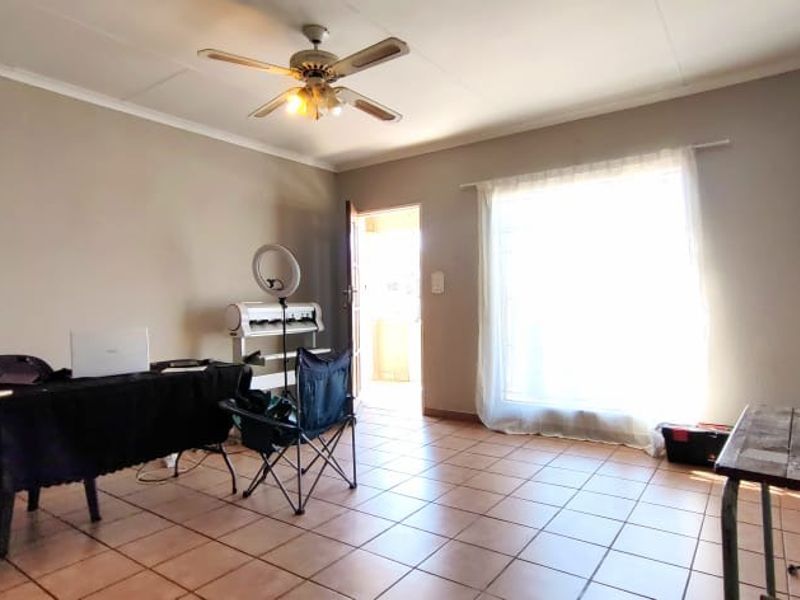 A living room area featuring tiled flooring, a ceiling fan, and a sliding glass door providing access to the exterior.