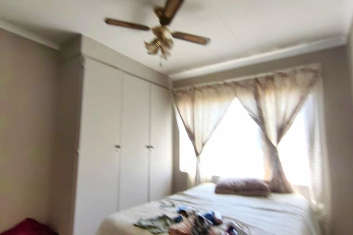 A bedroom featuring built-in cupboards, a ceiling fan, and coving detail.