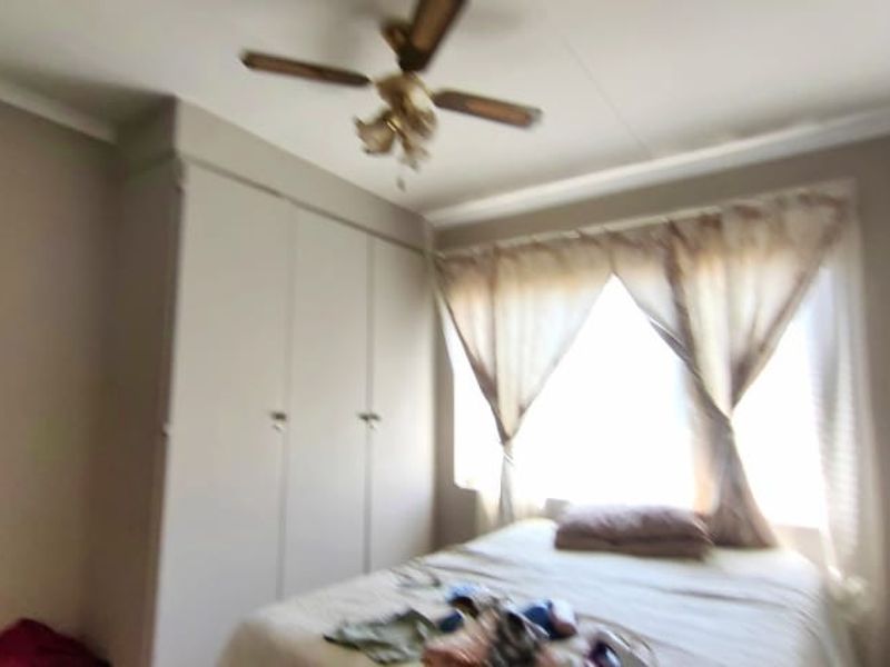 A bedroom featuring built-in cupboards, a ceiling fan, and coving detail.