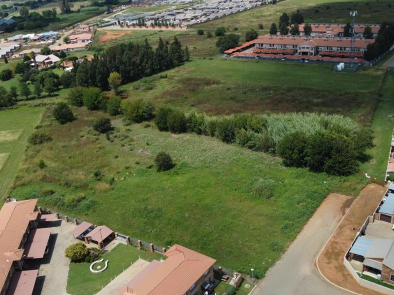 Aerial view of a vacant residential plot situated within an established suburban neighborhood, showing surrounding housing developments and access roads.
