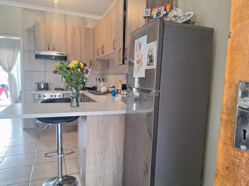 A functional kitchen featuring light wood-look cabinetry, a breakfast bar, tiled backsplash, and a built-in gas stove with an extractor fan.