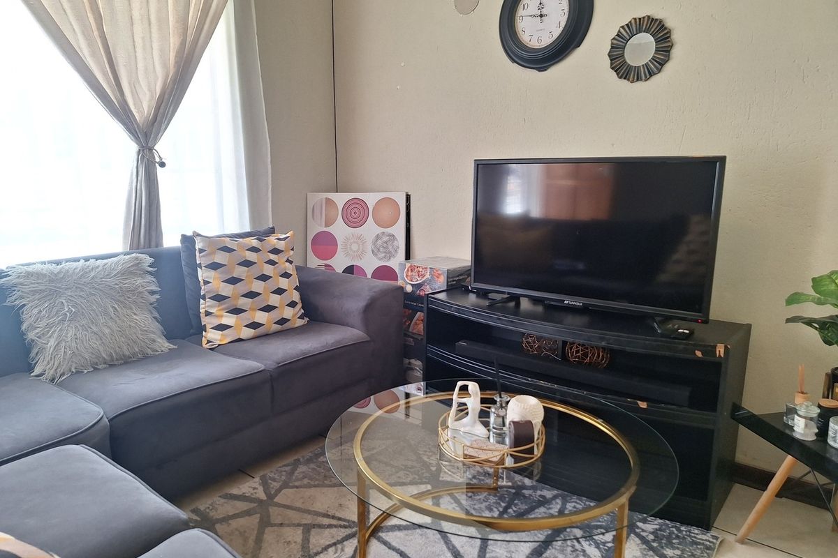 A cozy living room area featuring neutral wall finishes and natural light through window treatments.