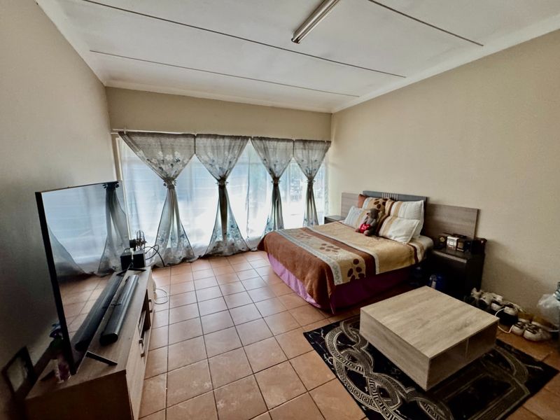 Spacious bedroom featuring tiled flooring, a built-in headboard, and a large window allowing for natural light.
