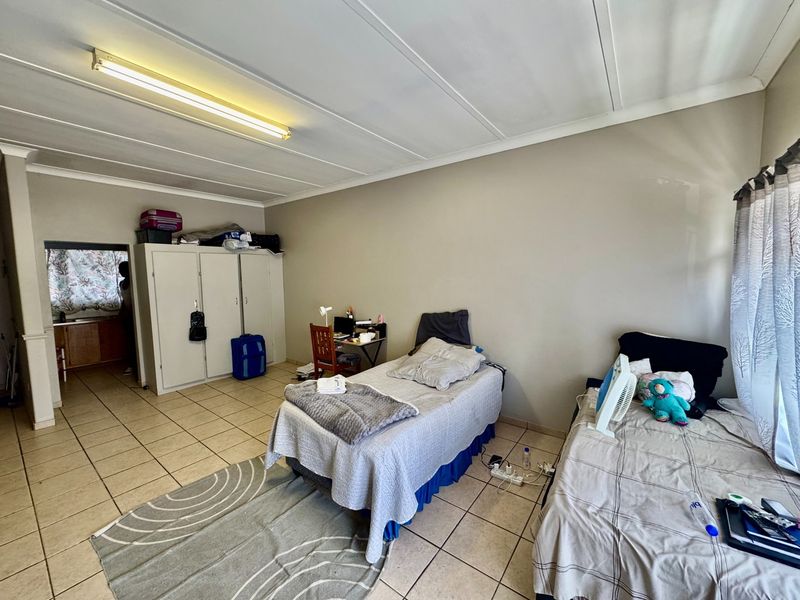 A bedroom featuring tiled flooring, built-in cupboards, and a coved ceiling. The space requires cosmetic updates to improve its overall condition and appeal.