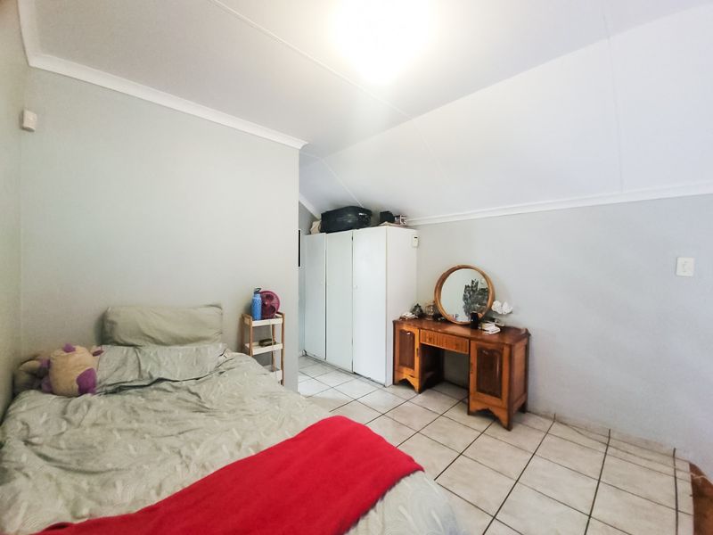 A bedroom featuring tiled flooring, a built-in wardrobe, and a sloped ceiling design.