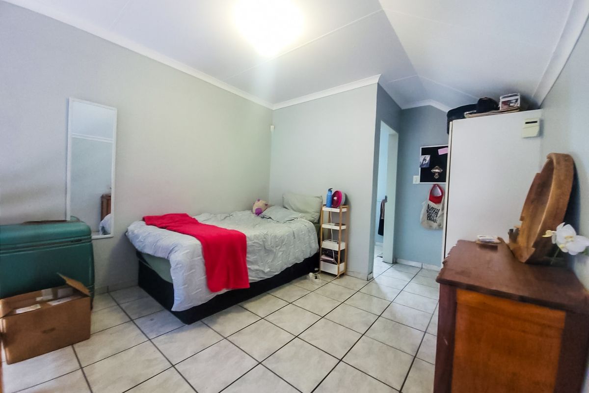 A bedroom featuring tiled flooring and coved ceilings, providing a functional living space with neutral wall finishes.