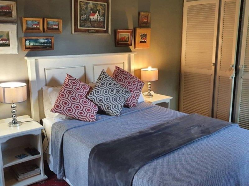 A cozy bedroom featuring built-in louvered closet doors and a neutral wall finish, providing a functional and comfortable sleeping space.
