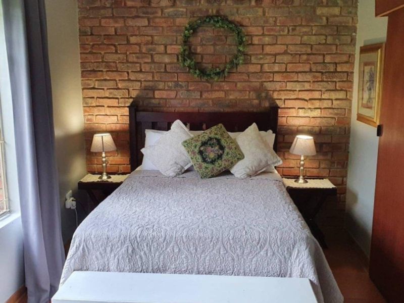 A cozy bedroom featuring a prominent exposed brick feature wall and durable tiled flooring.