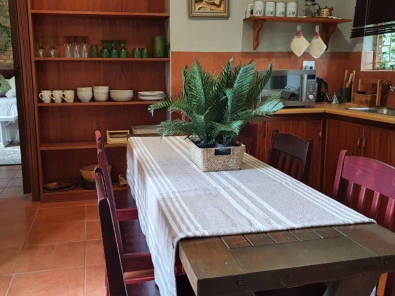 A functional kitchen featuring warm-toned wooden cabinetry, tiled flooring, and built-in shelving, providing ample storage and a classic, lived-in aesthetic.