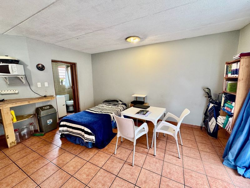 A bedroom featuring tiled flooring and direct access to an en-suite bathroom, offering a functional space in need of cosmetic updates.