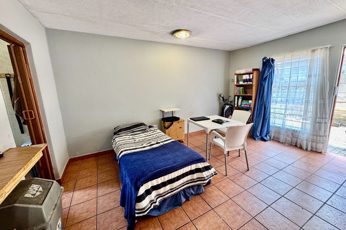 A functional bedroom featuring tiled flooring and a sliding glass door providing access to the exterior.