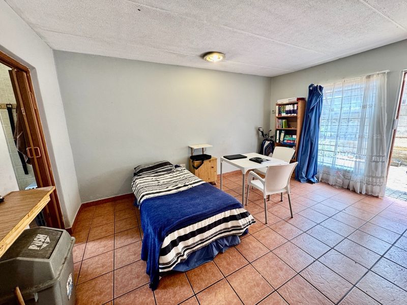 A functional bedroom featuring tiled flooring and a sliding glass door providing access to the exterior.