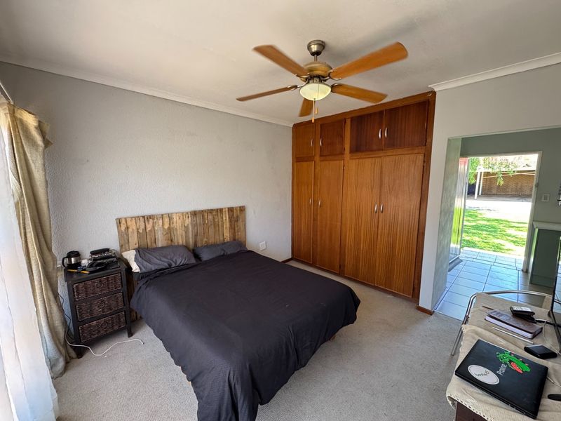 A bedroom featuring built-in wooden cupboards, a ceiling fan, and direct access to an outdoor patio area.
